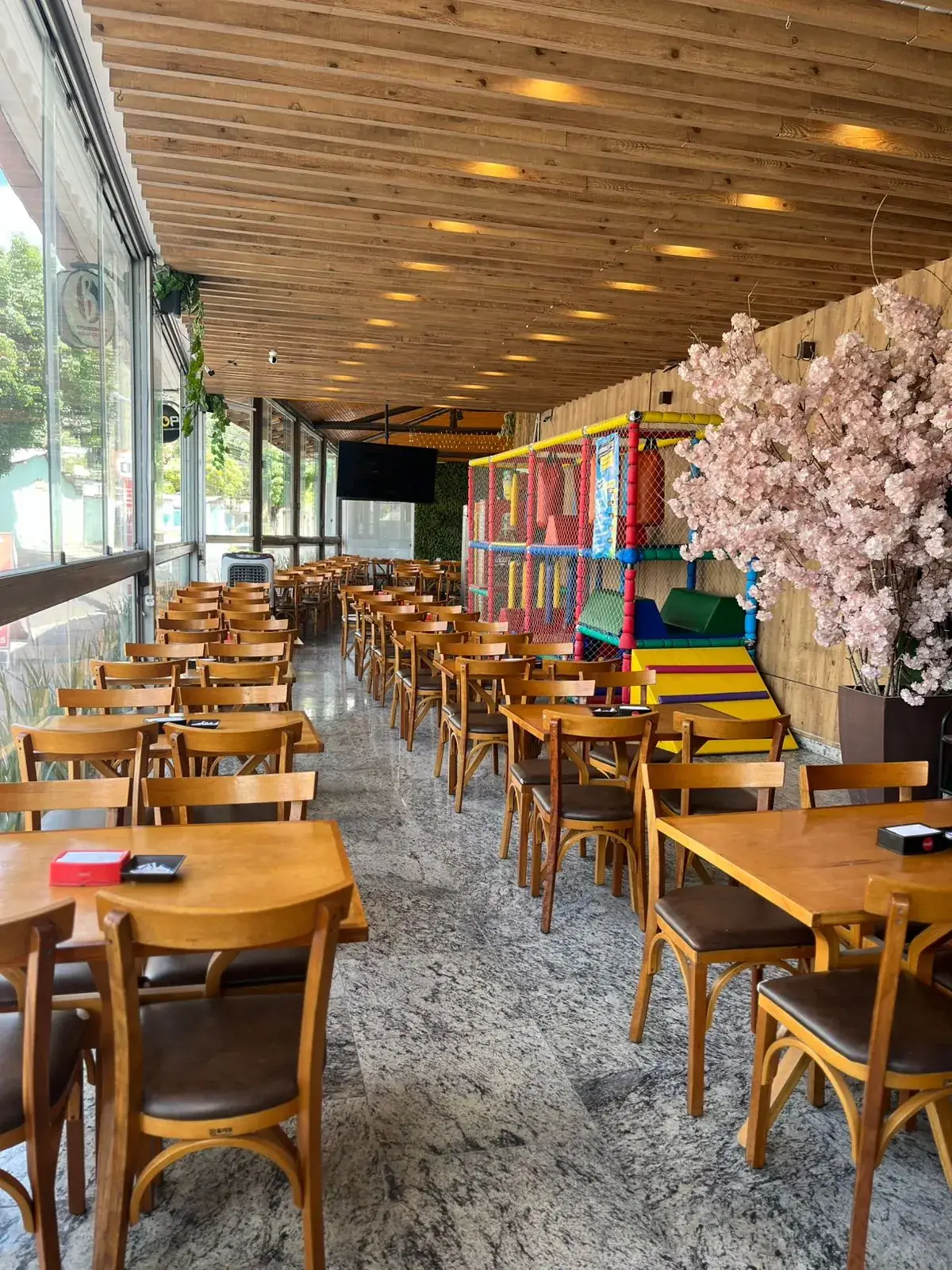 Salão do Gourmet Barão Eventos com mesas, espaço kids e cerejeira